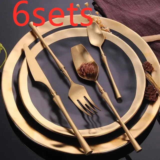 Stainless steel cutlery set with gold finish including knife, fork, spoon, and teaspoon on table