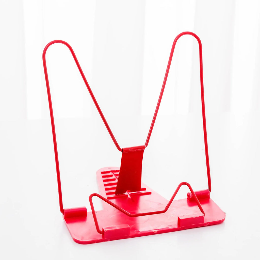 Multifunctional metal reading frame in red, green, and blue colours on a desk with a book.