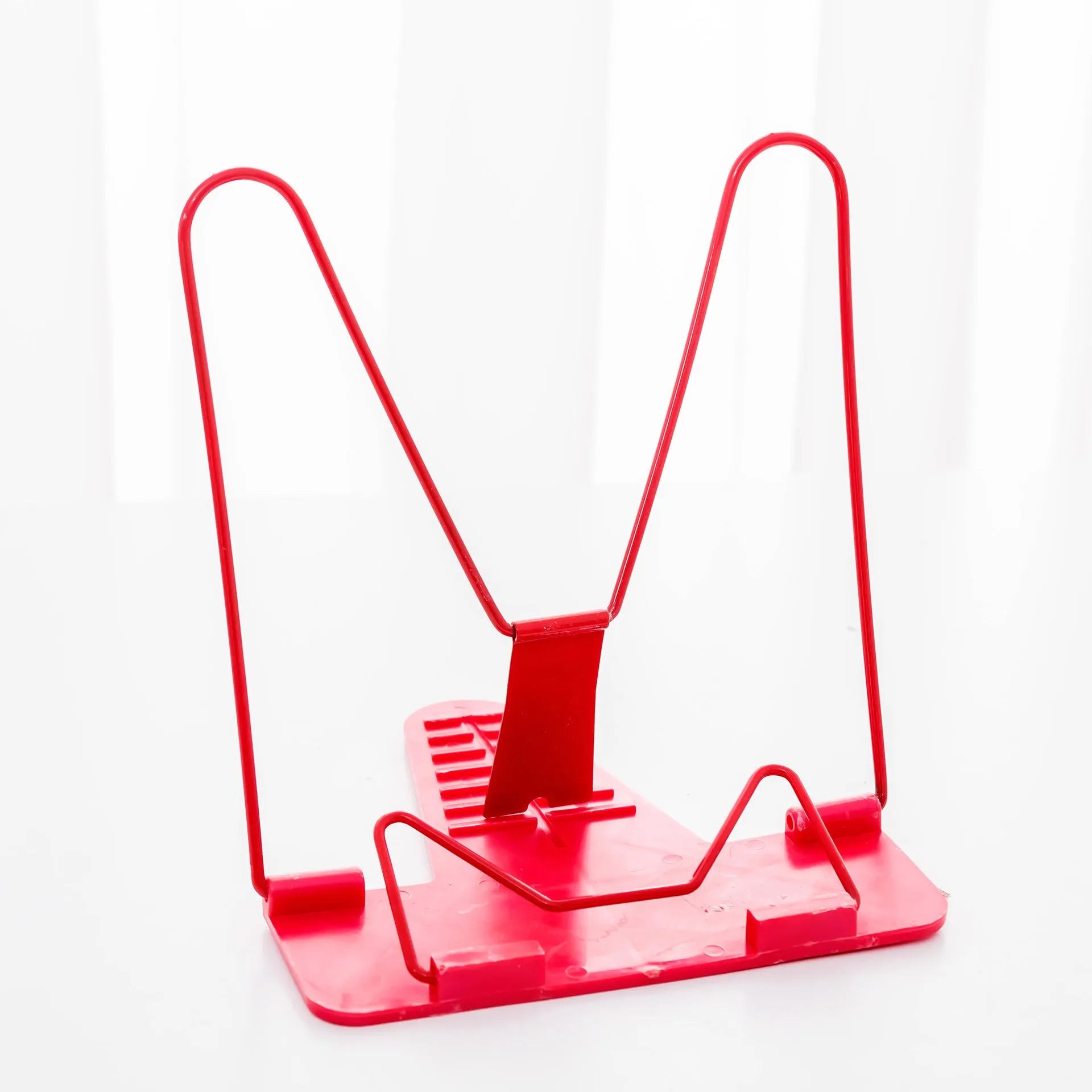 Multifunctional metal reading frame in red, green, and blue colours on a desk with a book.