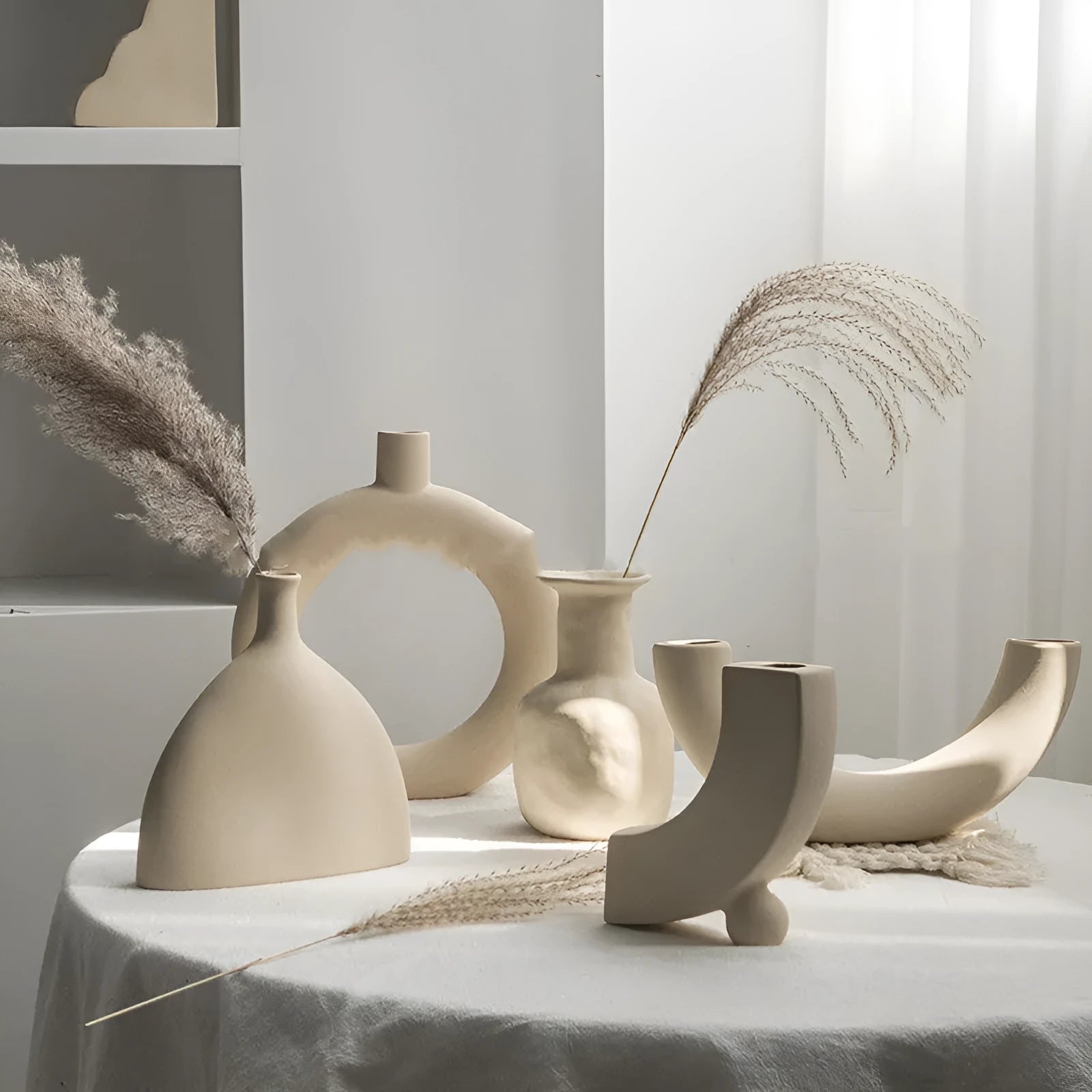 Unglazed matte ceramic vase for dried flowers in a neutral colour on a wooden table.