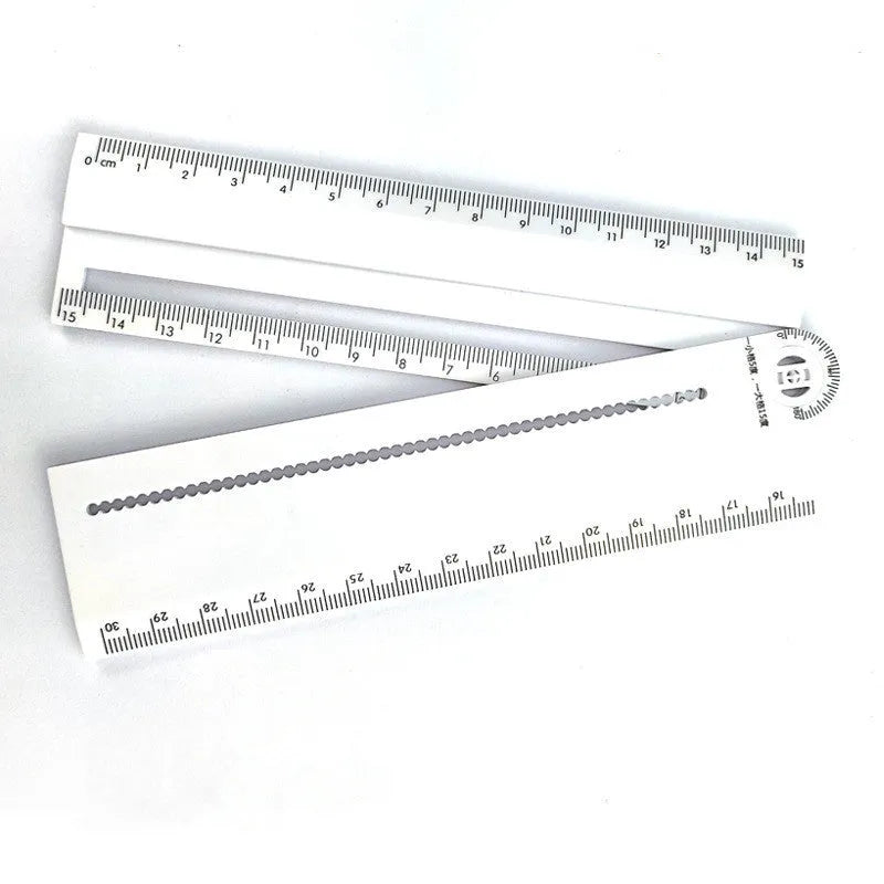 White plastic multi-function ruler measuring 30 cm in length on a flat surface.