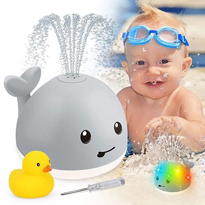 Grey and white cartoon whale bath toy floating in water with spray fountain and LED lights
