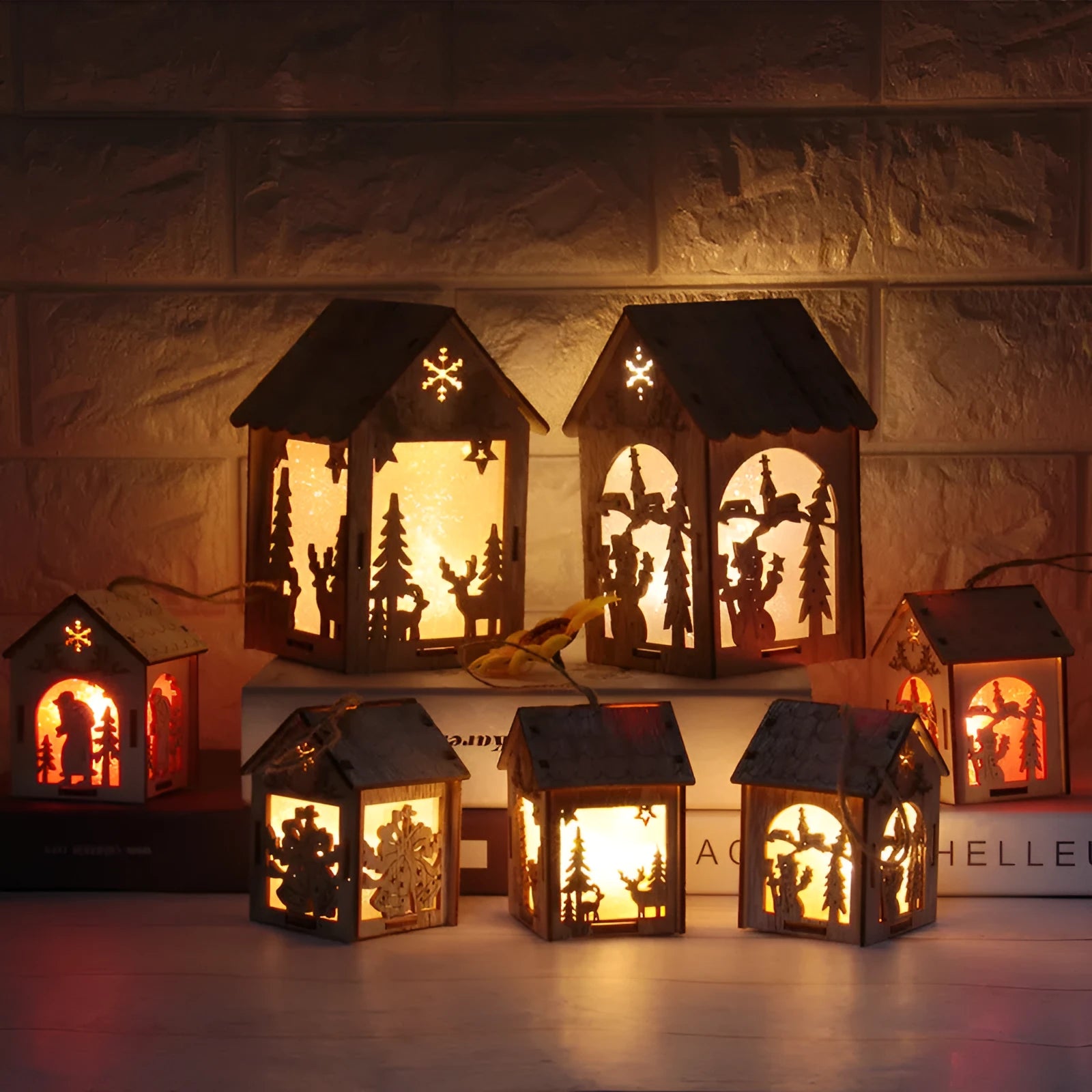 Set of three small wooden Christmas house decorations including a log bell and snowman design on a rustic surface.