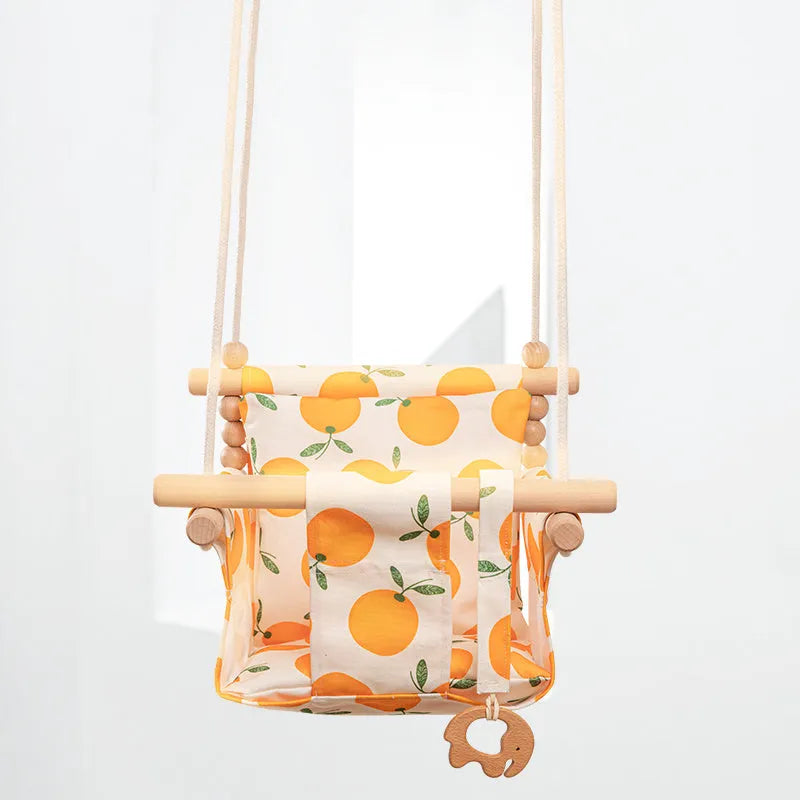 Natural beige cotton canvas baby swing chair with wooden seat and decorative tassel pattern, hanging indoors.
