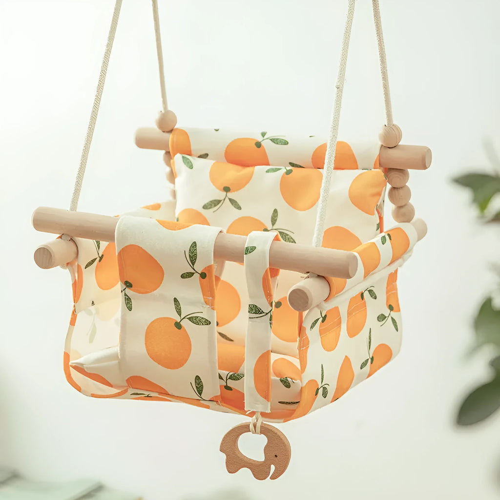 Natural beige cotton canvas baby swing chair with wooden seat and decorative tassel pattern, hanging indoors.