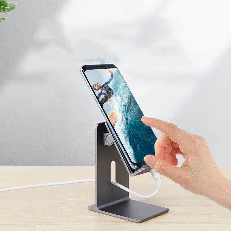 Alloy universal mobile phone and tablet stand in dark space grey colour on a wooden desk.