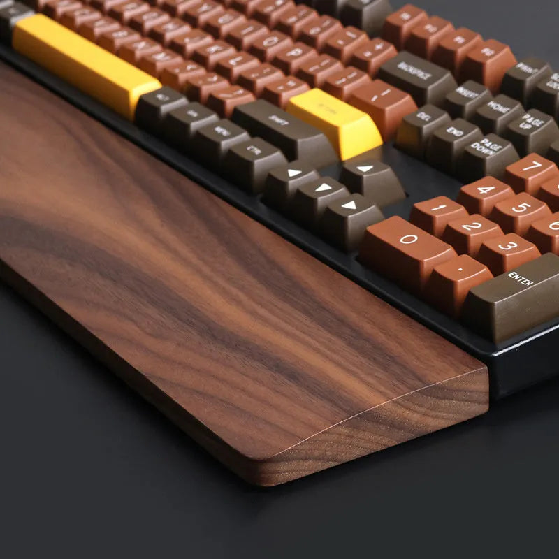Solid walnut wood wrist rest for mechanical keyboard on a wooden desk