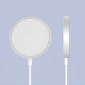 Silver metallic Magsafe magnetic wireless charger for iPhone on a wooden desk.