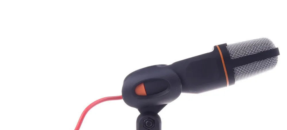 Black wired PC microphone with an adjustable clip-on holder on a desk.