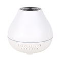 Round white Bluetooth aroma diffuser and humidifier with a colour-changing night light on a table.