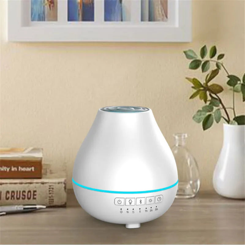 Round white Bluetooth aroma diffuser and humidifier with a colour-changing night light on a table.