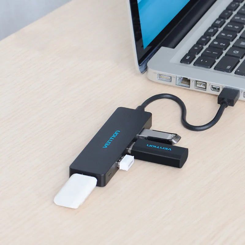 Black 4-port USB 3.0 hub with a short braided cable and nickel-plated connectors on a desk.