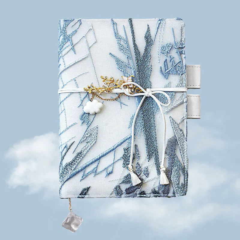 Glacier embroidery design on a fabric cover notebook lying open on a grid page.