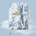 Glacier embroidery design on a fabric cover notebook lying open on a grid page.