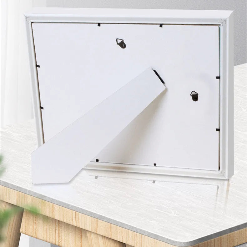 Modern DIY baby hand and foot print anniversary frame in white, shown on a shelf.