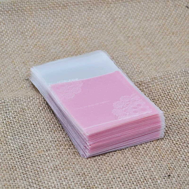 Pack of 100 small pink self-adhesive plastic bags for soap or snack packaging.
