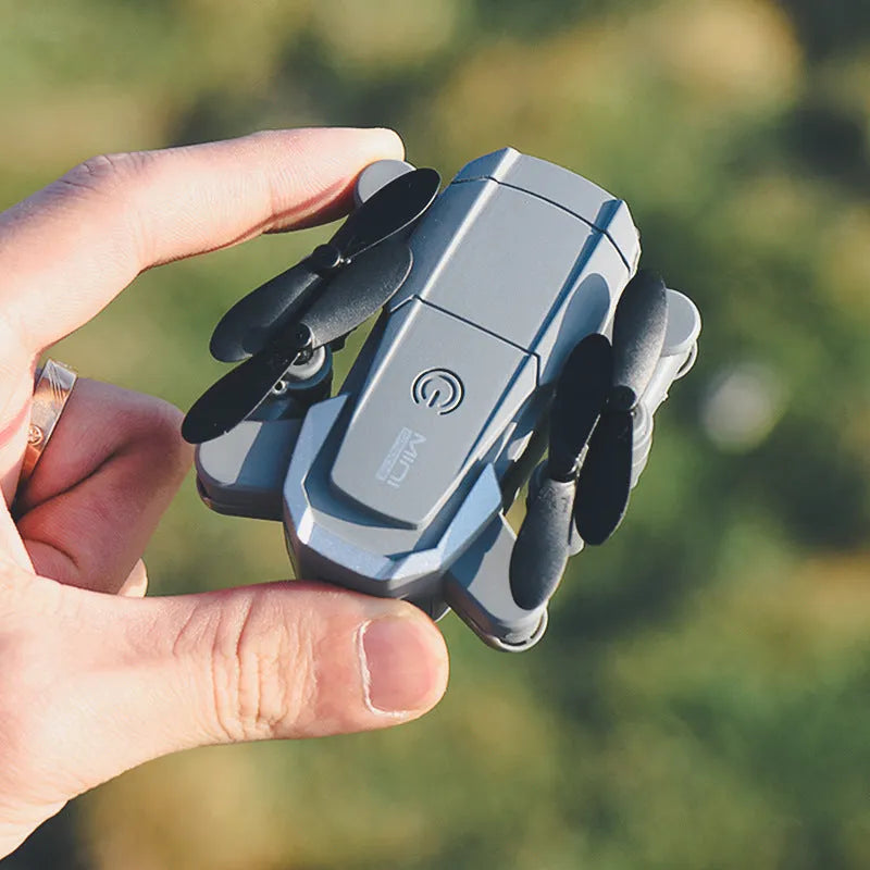 Mini folding 4K camera drone with plastic body and storage bag on a desk