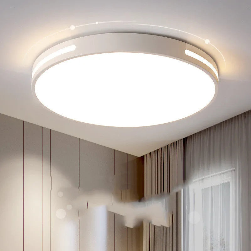 Round modern acrylic LED ceiling lamp with remote control on a white bedroom ceiling