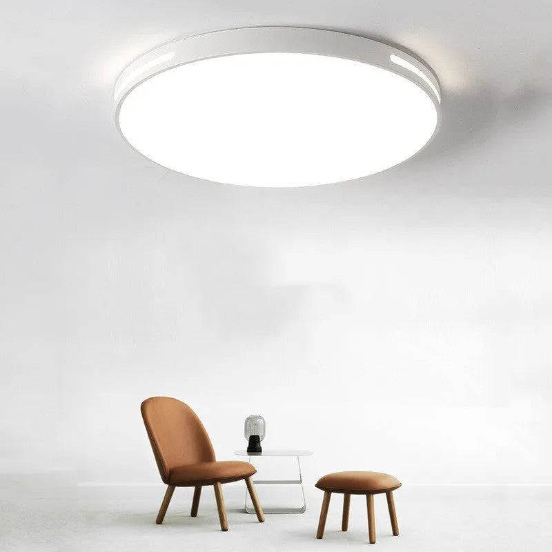 Round modern acrylic LED ceiling lamp with remote control on a white bedroom ceiling