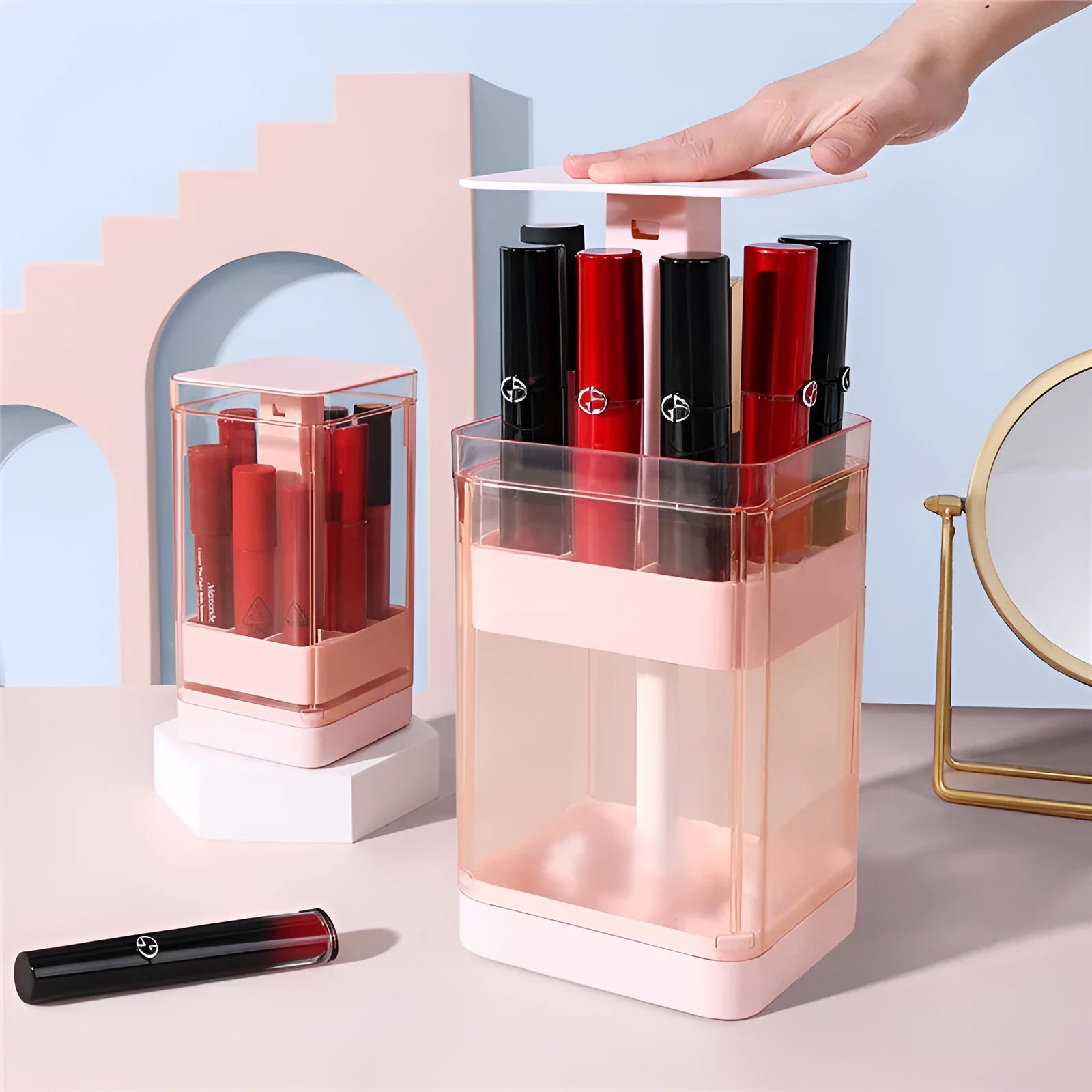 Pink press-lift lipstick storage box with dust cover open, showing 12 individual compartments.