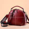 Round leather handbag with double soft handles and a zipper, shown in wine red colour.