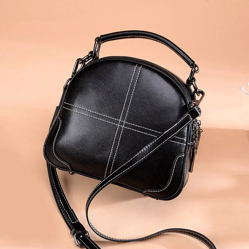 Round leather handbag with double soft handles and a zipper, shown in wine red colour.