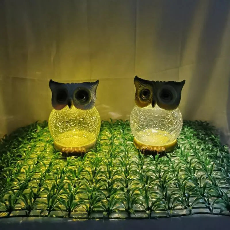 White solar-powered LED owl garden light with detailed features, placed outdoors beside plants