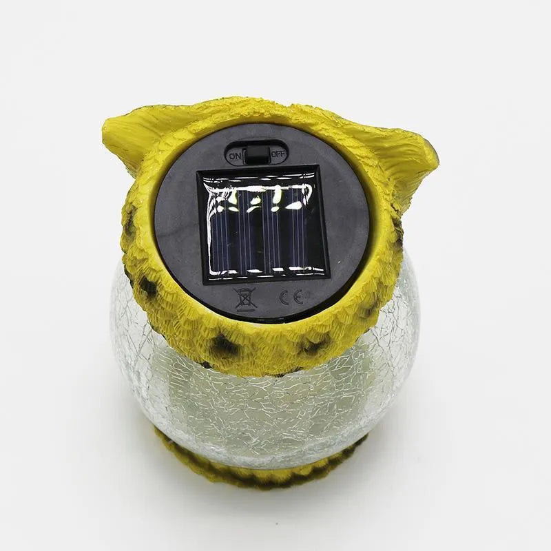 White solar-powered LED owl garden light with detailed features, placed outdoors beside plants