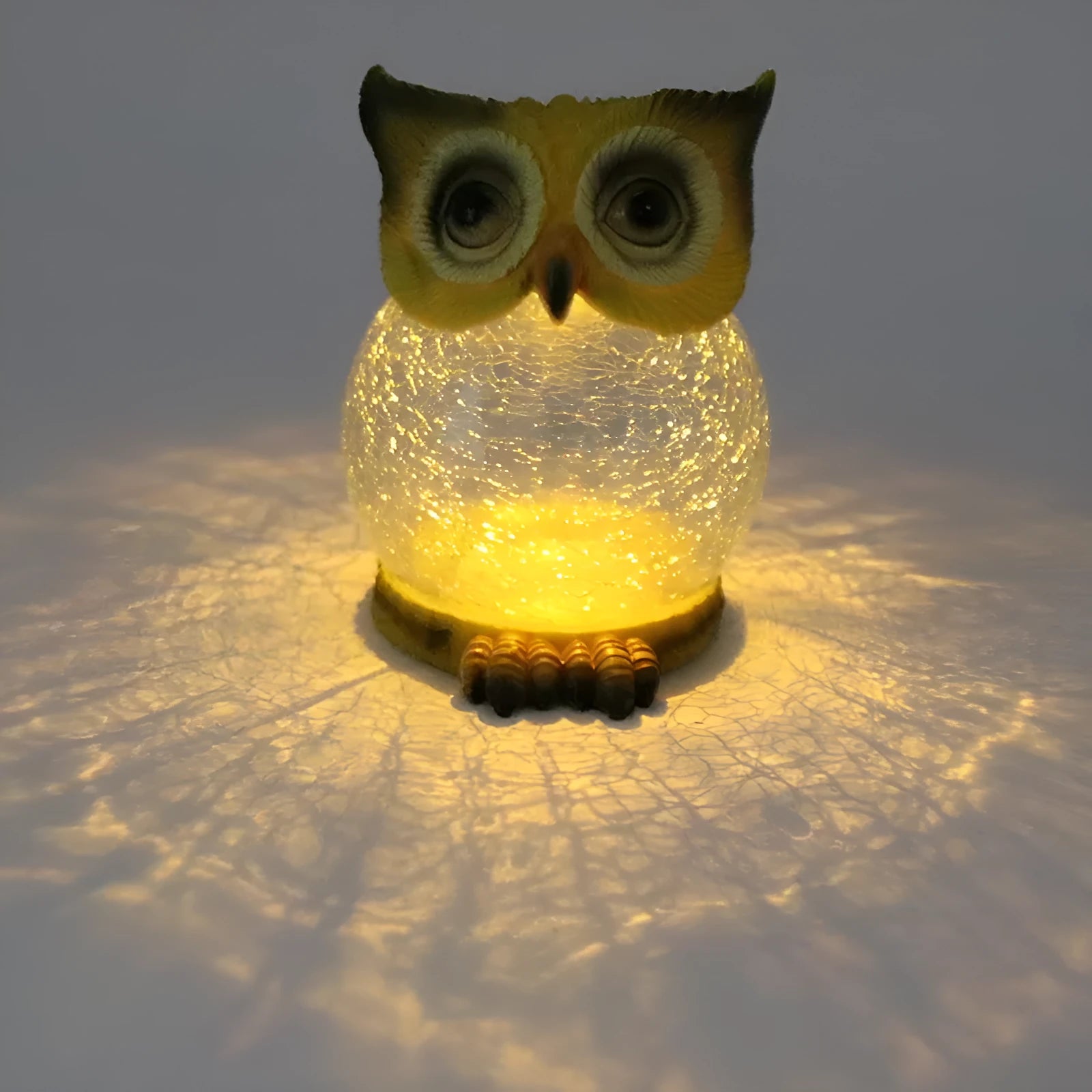White solar-powered LED owl garden light with detailed features, placed outdoors beside plants