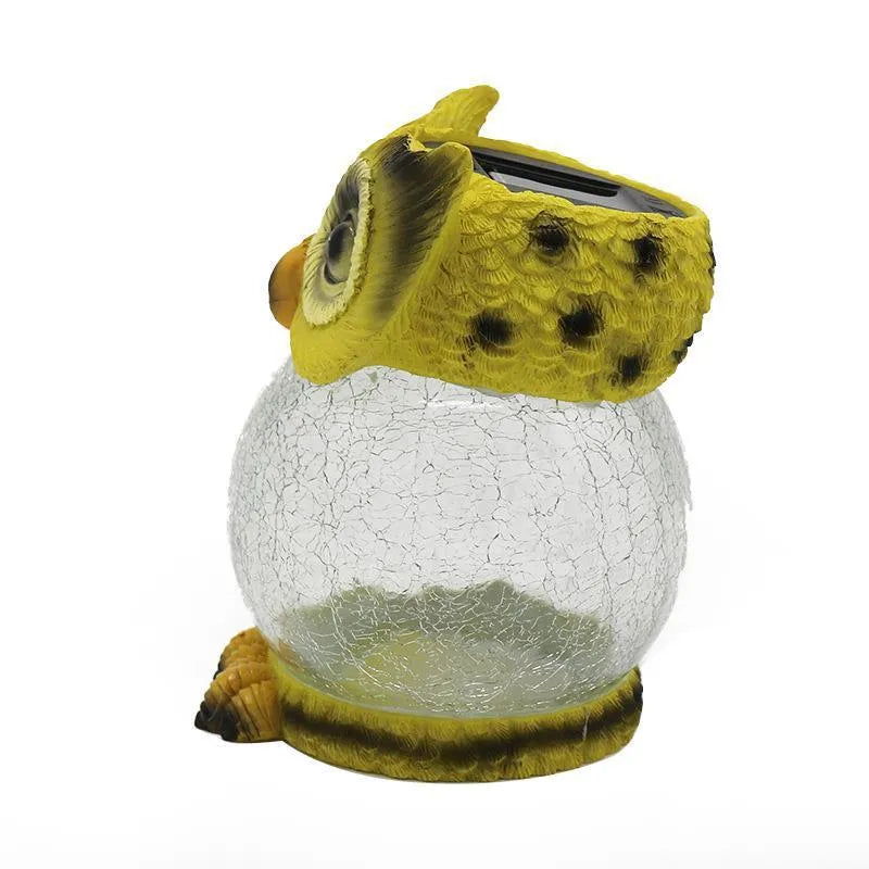 White solar-powered LED owl garden light with detailed features, placed outdoors beside plants