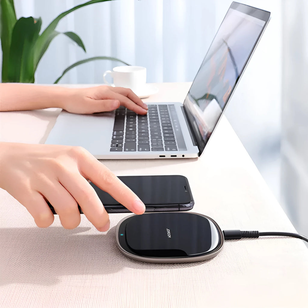 Black or white 15W wireless charging pad with zinc alloy and glass construction on a desk.