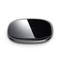 Black or white 15W wireless charging pad with zinc alloy and glass construction on a desk.