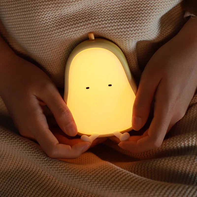 PEAR warm yellow silicone bedside night light with ABS base on a table.