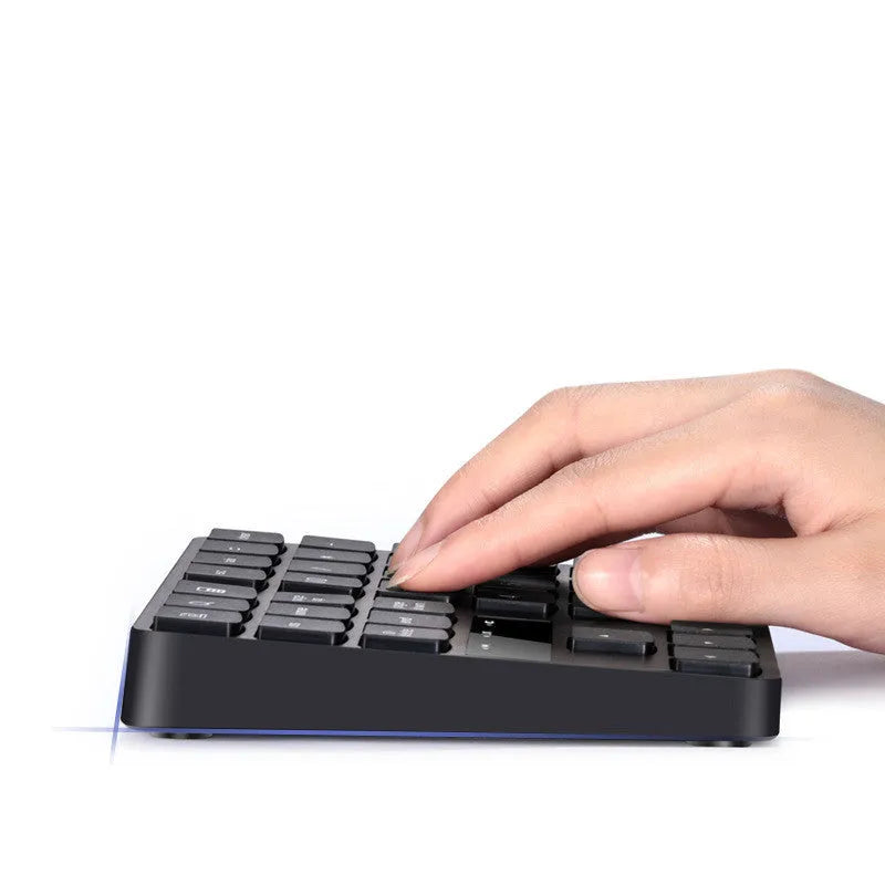 Black 35-key wireless numeric keyboard on desk with USB receiver and charging cable