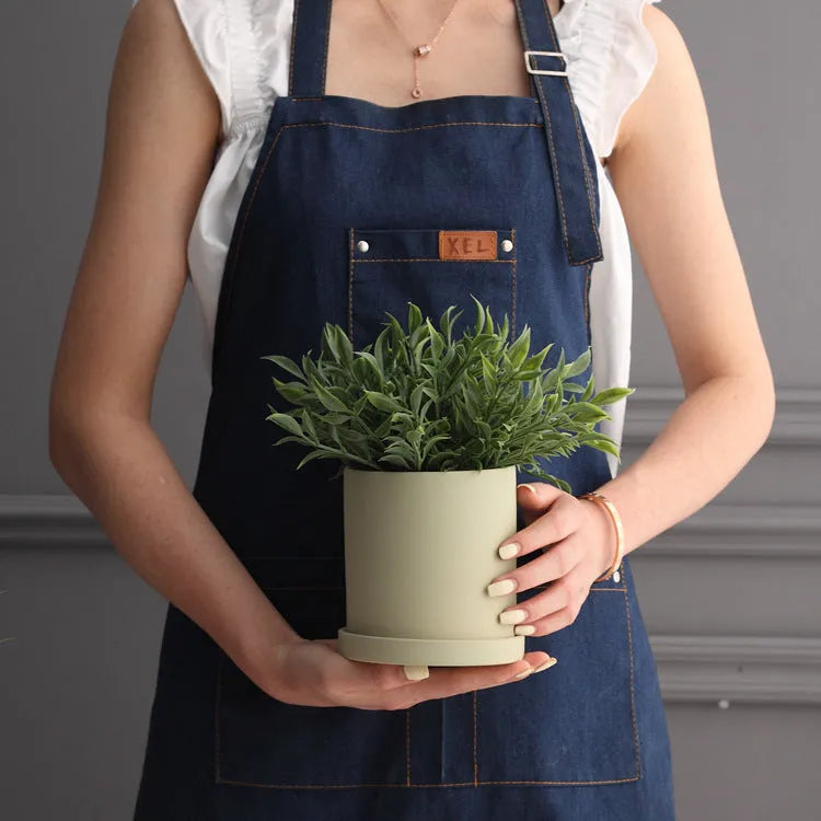 Colourful cylindrical ceramic succulent planter with drainage hole on a wooden surface