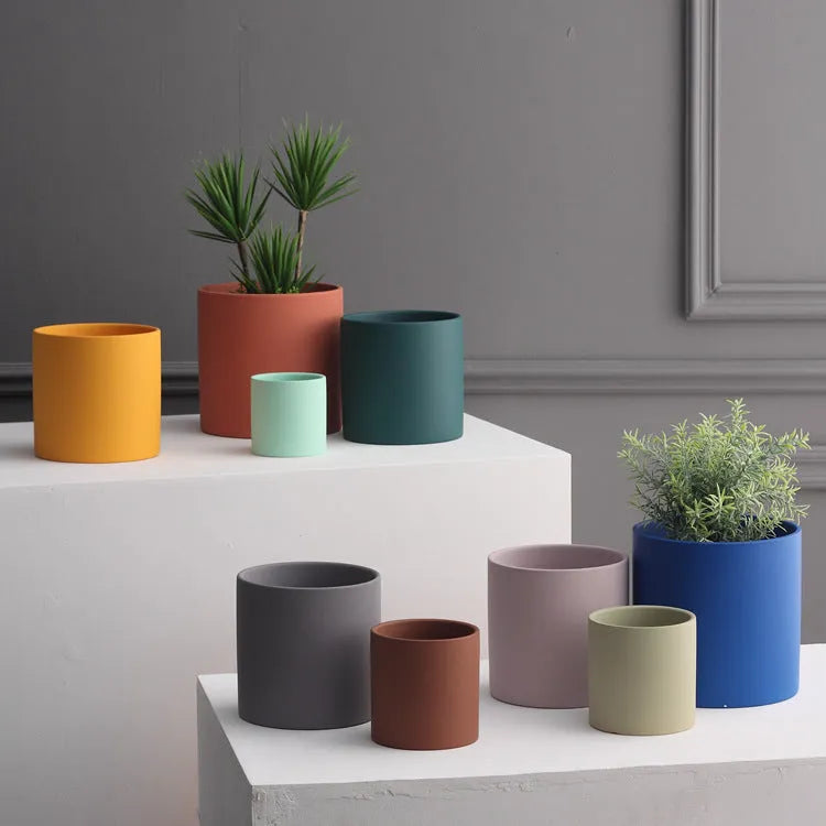 Colourful cylindrical ceramic succulent planter with drainage hole on a wooden surface