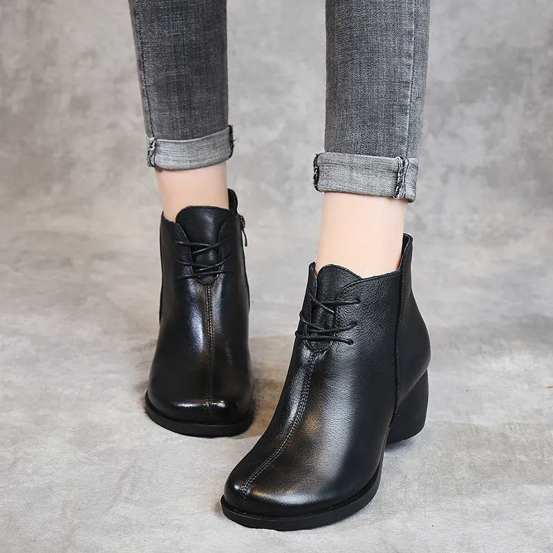 Women's black leather Martin boots with a thick mid-heel and round toe on a rubber sole.