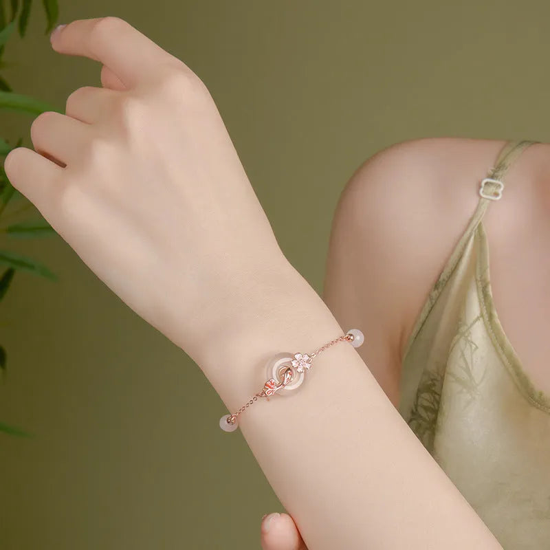 Women's sterling silver bracelet with Chinese floral design, white chalcedony crystal, and koi fish elements