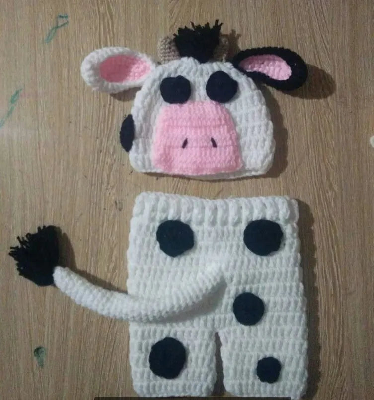 White hand-knitted baby cow suit set with matching hat and trousers for newborns.