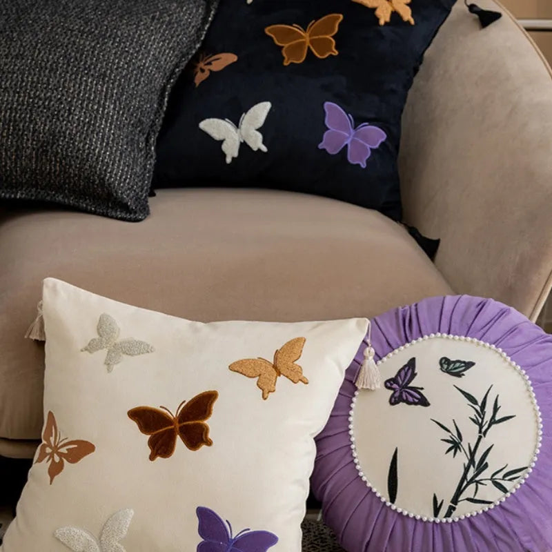 Square beige, black, and purple cushion with Chinese style embroidered butterfly pattern.