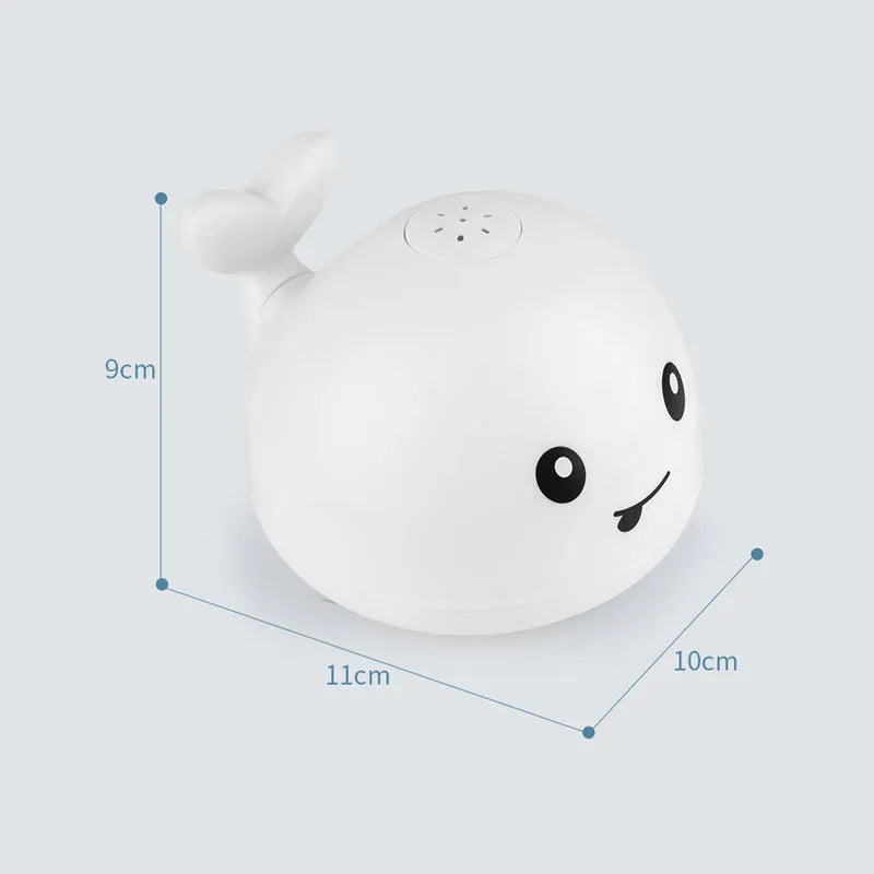 Whale-shaped electric bath toy spraying water with flashing lights, floating in baby bathtub