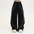Black trousers with vertical stripes and pleated detail on the legs, showing a loose wide-leg fit.