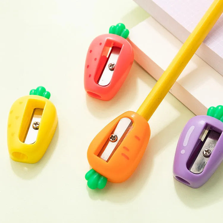 Four fruit and vegetable shaped mini pencil sharpeners in random colours on a light surface