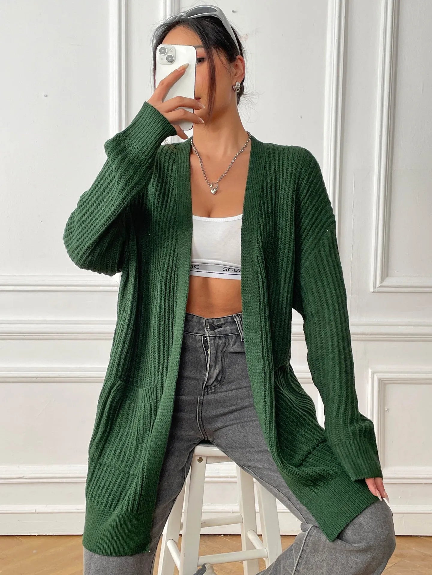 A woman's loose-fit mid-length cardigan in a solid colour, shown on a hanger.