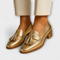 Gold PU leather low heel slip-on pumps with tassel detail and square toe on woman's feet