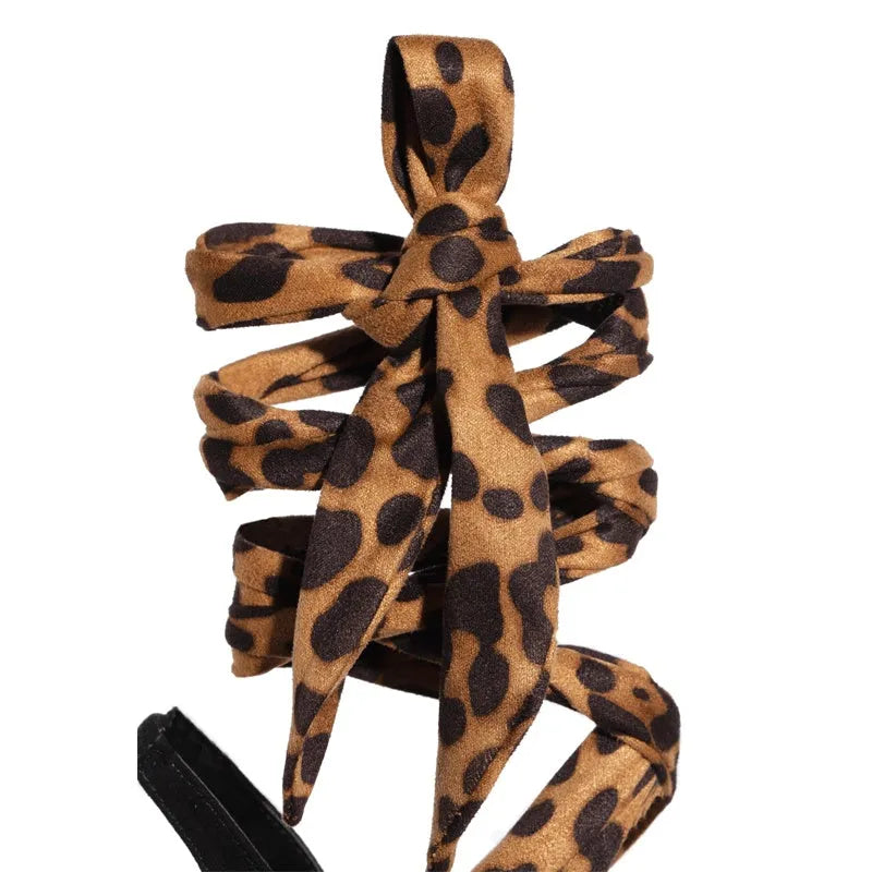 Light brown women's high-heeled sandals with leopard print and Roman cross straps on a fine high heel.