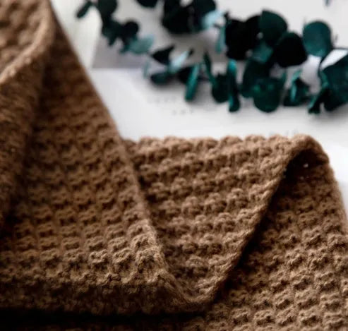 Nordic style knitted acrylic blanket with fringed edges on a sofa, showing its 130x170cm size and plain texture.