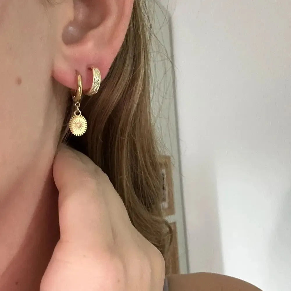 A pair of stainless steel ellipse-shaped stud earrings with butterfly clips on a white background.