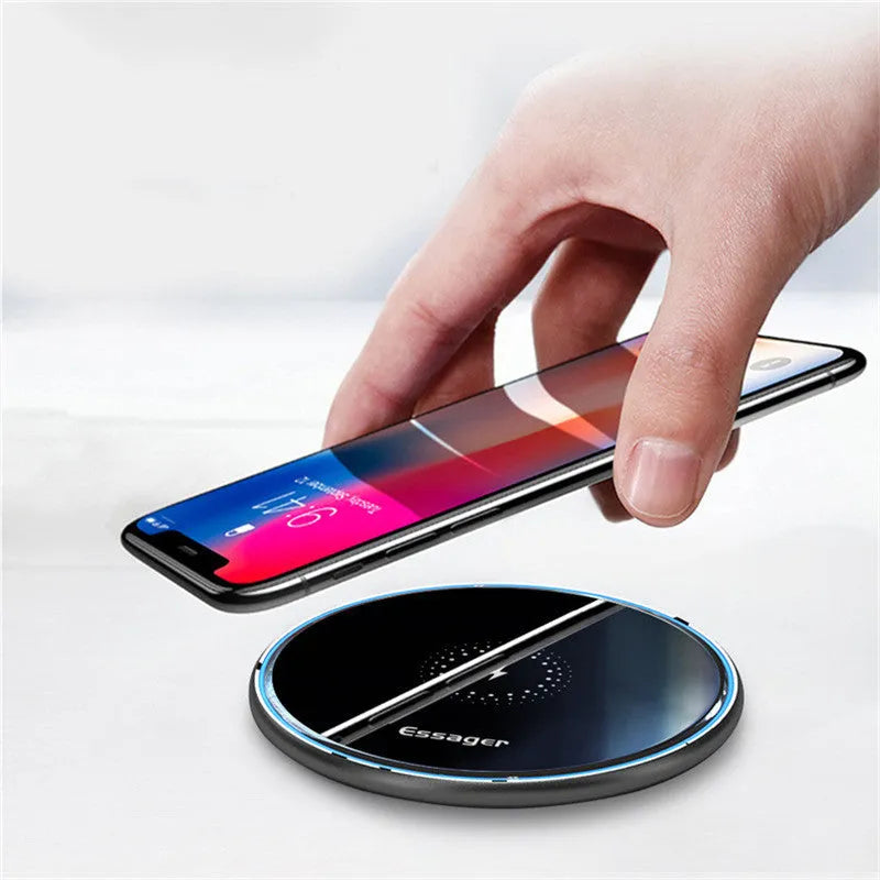 Black wireless charging pad on table with phone charging and blue LED indicator light