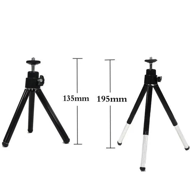Black mini desktop camera tripod with extended legs and a U-shaped phone clip attached, on a white background.